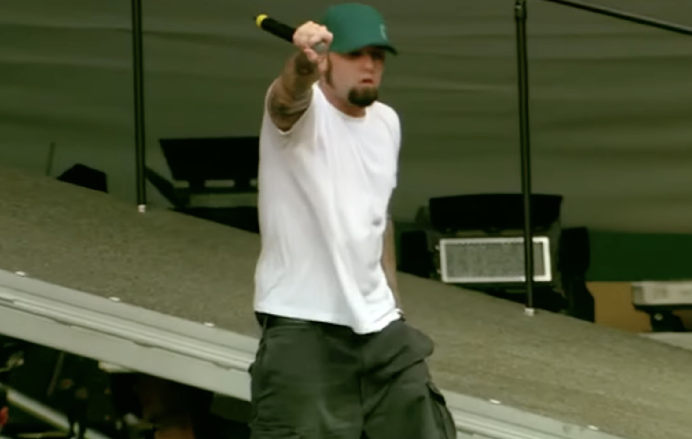 Fred Durst, frontman of Limp Bizkit, performing live on stage in 2003 with microphone, energetic stance, and dramatic stage lighting.