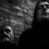 Studio promotional photo of Godflesh featuring members Justin Broadrick and G. C. Green posed against a dark industrial backdrop.