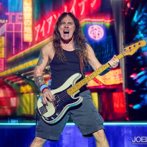Steve Harris, bassist of Iron Maiden, performing live on stage with his signature bass guitar under dramatic concert lighting