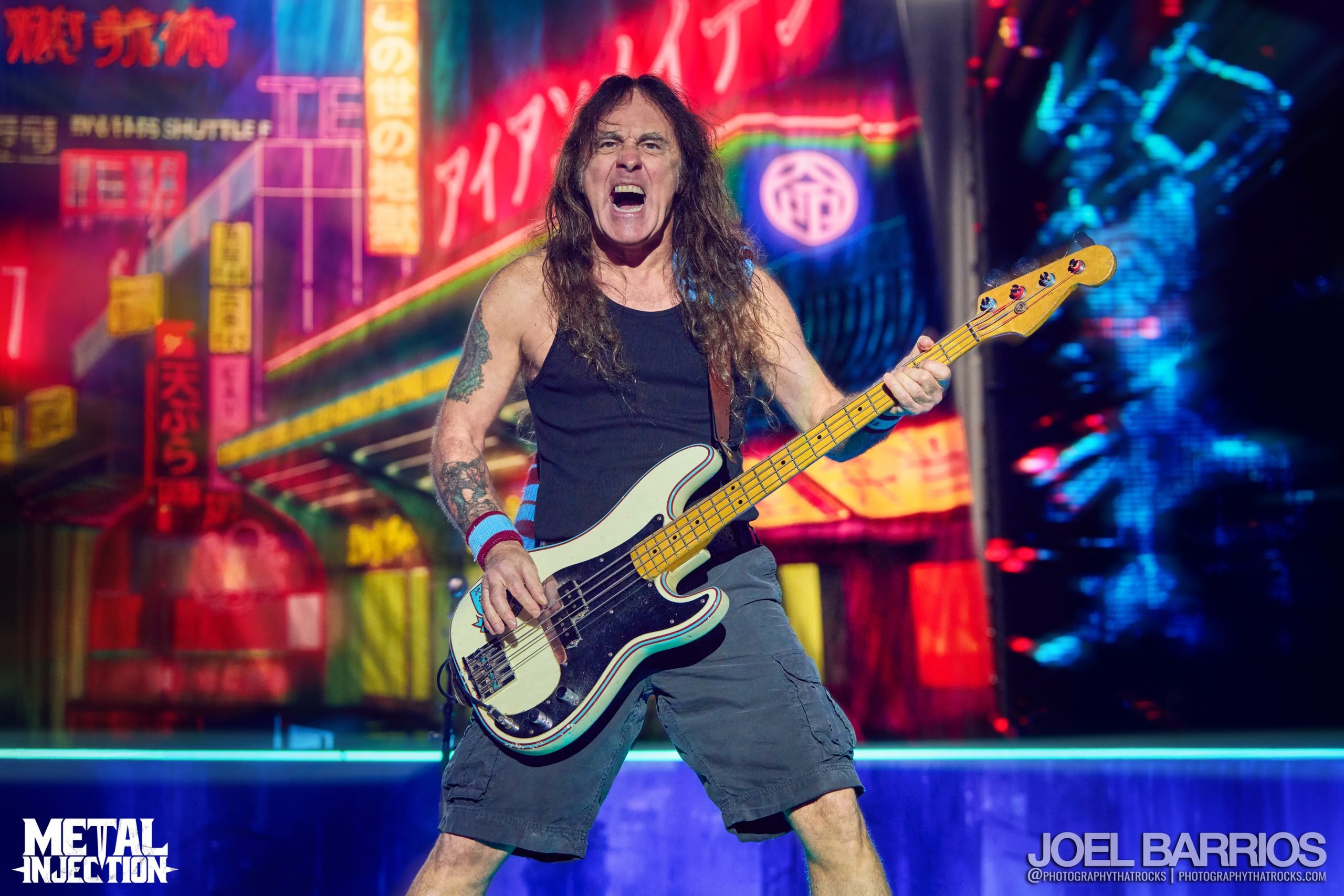 Steve Harris, bassist of Iron Maiden, performing live on stage with his signature bass guitar under dramatic concert lighting