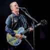 Josh Homme, frontman of Queens of the Stone Age, performing live on stage with guitar and energetic lighting