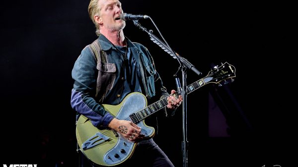 Josh Homme, frontman of Queens of the Stone Age, performing live on stage with guitar and energetic lighting