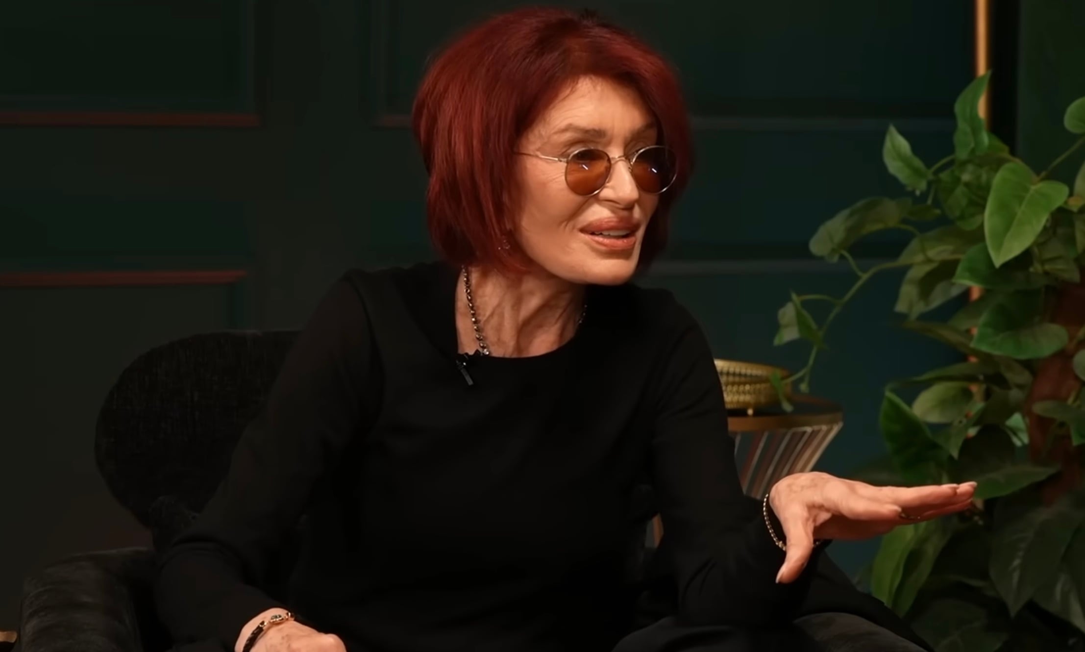 Sharon Osbourne speaking into a microphone during a recording session of The Osbournes podcast in a studio setting.