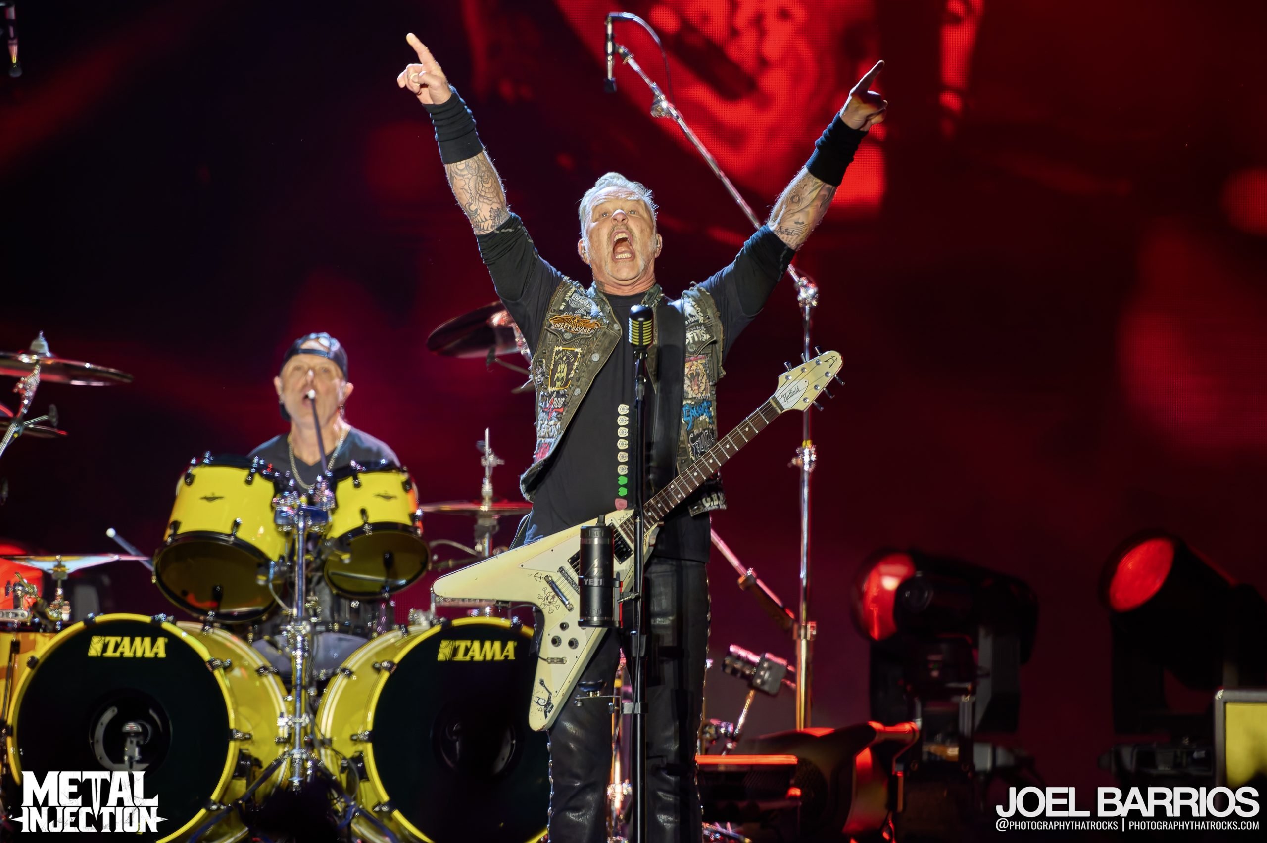 A photo of James Hetfield and Lars Ulrich performing with Metallica live on stage.