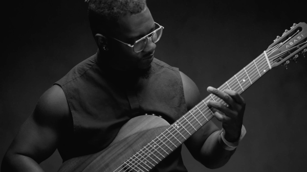 Tosin Abasi, guitarist and founder of Animals as Leaders, playing electric guitar on stage with focused technique