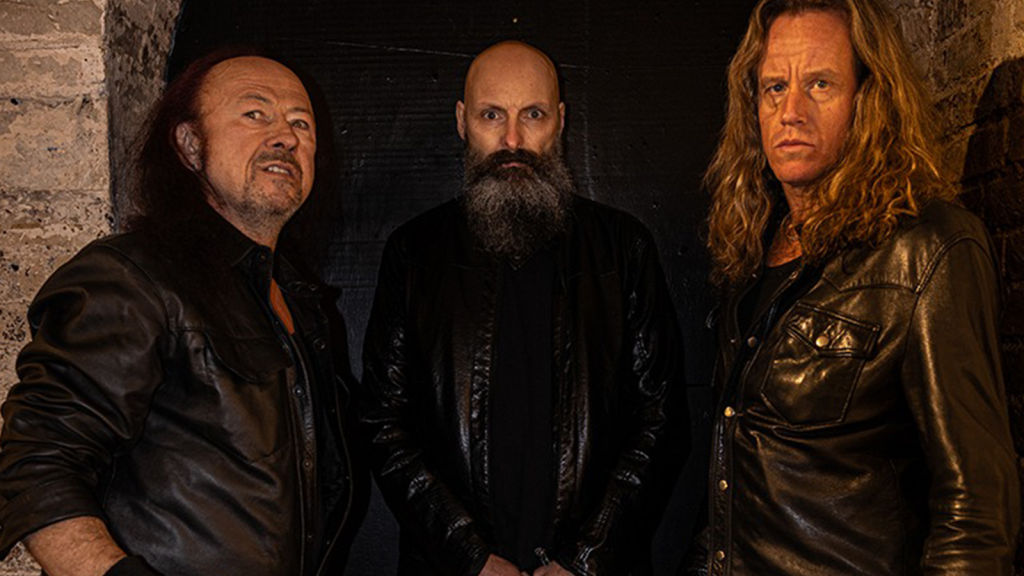 Venom band lineup in 2026 featuring Cronos on bass and vocals with guitarist Rage and drummer Dante.