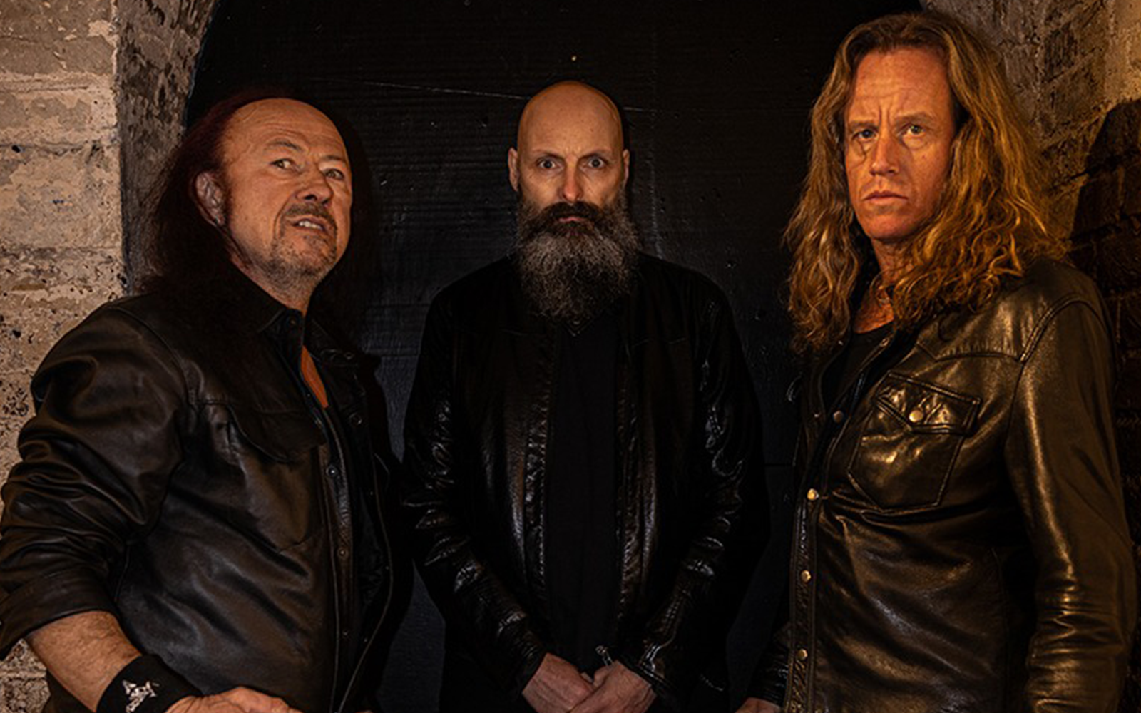 Venom band lineup in 2026 featuring Cronos on bass and vocals with guitarist Rage and drummer Dante.